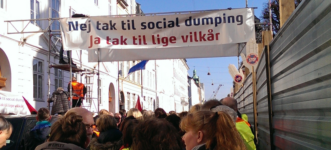 Bild på en folkmassa, banderoll med text på Danska nej tack till social dumping. Ja tack till lika villkor